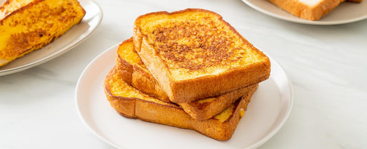 Classic French toast stacked on a white plate, cooked to a golden-brown finish.
