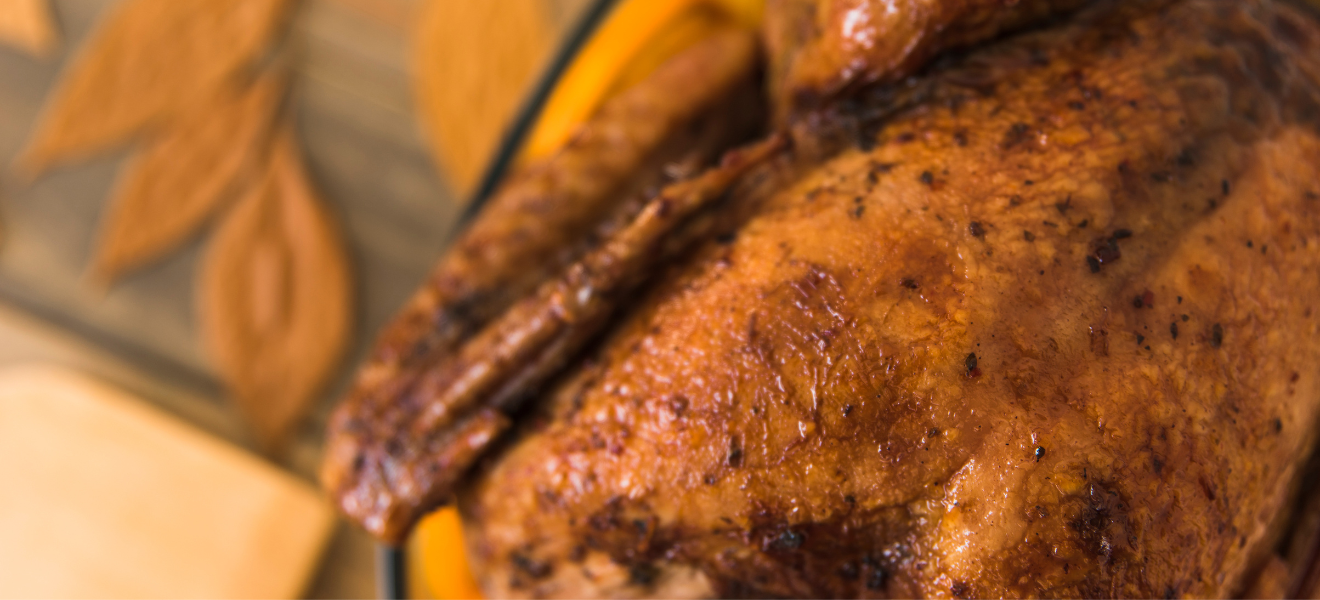 Close-up of golden rotisserie chicken with crisp, seasoned skin resting on a platter.