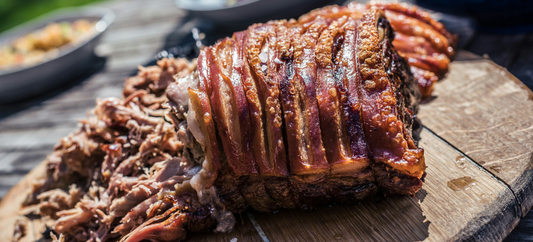 Tender smoked pulled pork with crackling prepared in a smoker and served on a rustic wooden board.