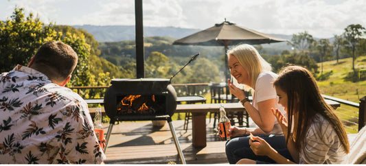 People enjoying snacks and drinks on a deck with an Ozpig Big Pig burning in the background.