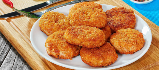 Golden, crispy chicken rissoles served on a white plate, ready to eat.