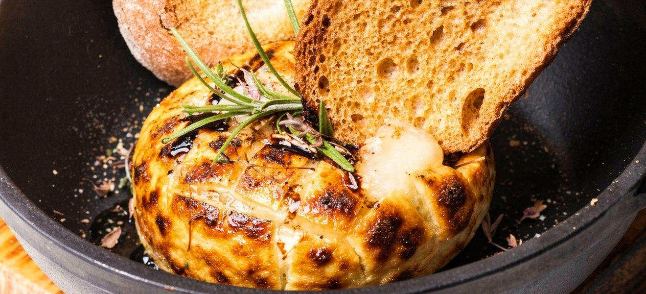 Smoked cream cheese in a skillet, bubbling and golden, topped with glaze and served with toasted bread.