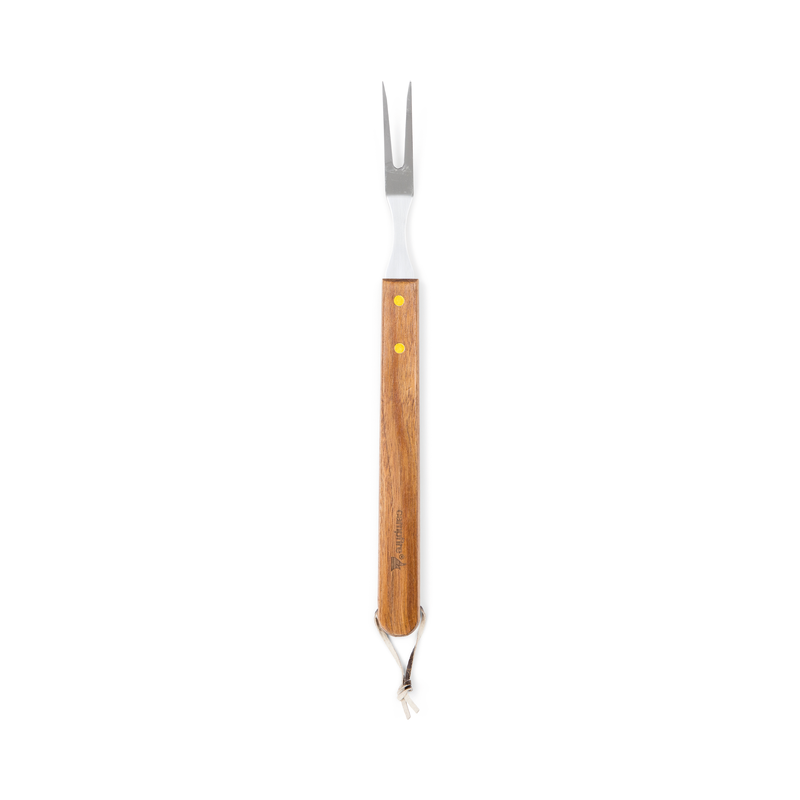The Campfire 22pc BBQ Set includes a metal carving fork with two prongs and a long wooden handle, accented by two yellow rivets and finished with a leather strap at the end. Photographed on a white background, this durable stainless steel fork is a practical addition for reliable outdoor cooking.