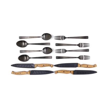 The Campfire 12pc Cutlery Set showcases four black stainless steel spoons and forks, complemented by three knives with elegant acacia wood handles and matching black blade covers, all beautifully presented against a white background.