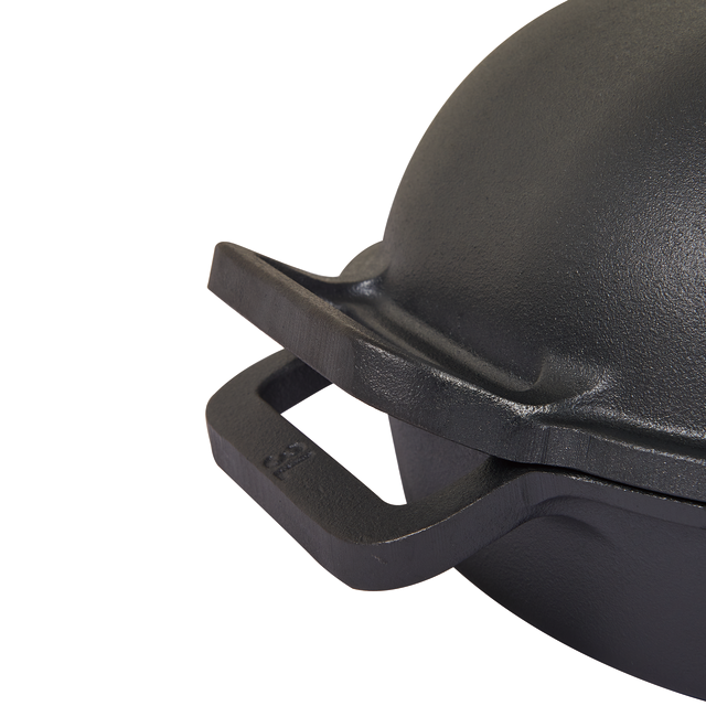 Close-up of the Campfire Combo Camp Oven, a black pre-seasoned cast iron oven featuring a curved lid and one rectangular handle, with a smooth matte texture—perfect for campfire cooking.
