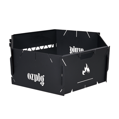 The Ozpig 3-in-1 Flat Pack Fire Pit is a black metal portable fire pit with a hexagonal design, featuring handles and interlocking panels. The sides are cut out with the "Ozpig" name and a flame icon, making it ideal for outdoor adventures.