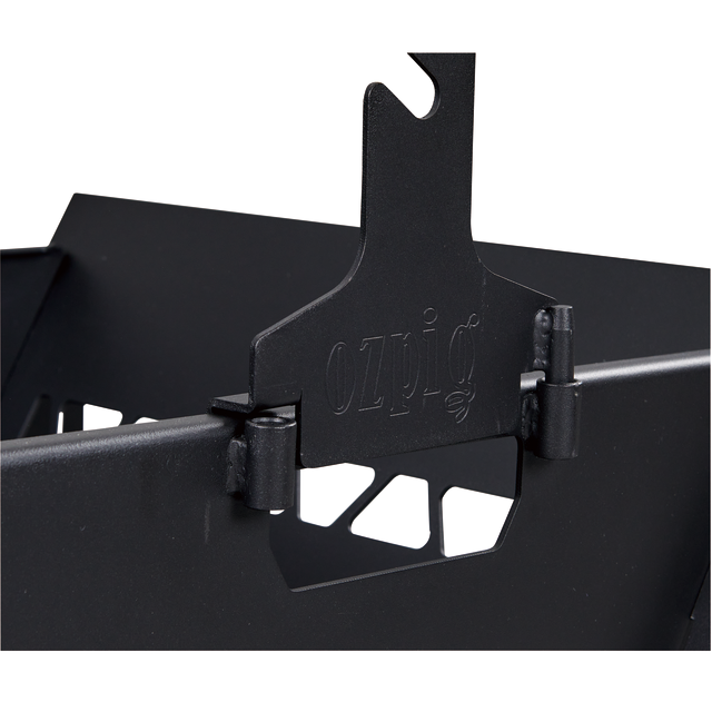 Close-up of a black metal hinge mechanism, partially attached to a box or container, with geometric cutouts and the word "OZpig" etched on the metal surface—an essential detail from the Ozpig Fire Pit Rotisserie Kit by Ozpig, designed to elevate your outdoor cooking experience with authentic wood-fired flavour.