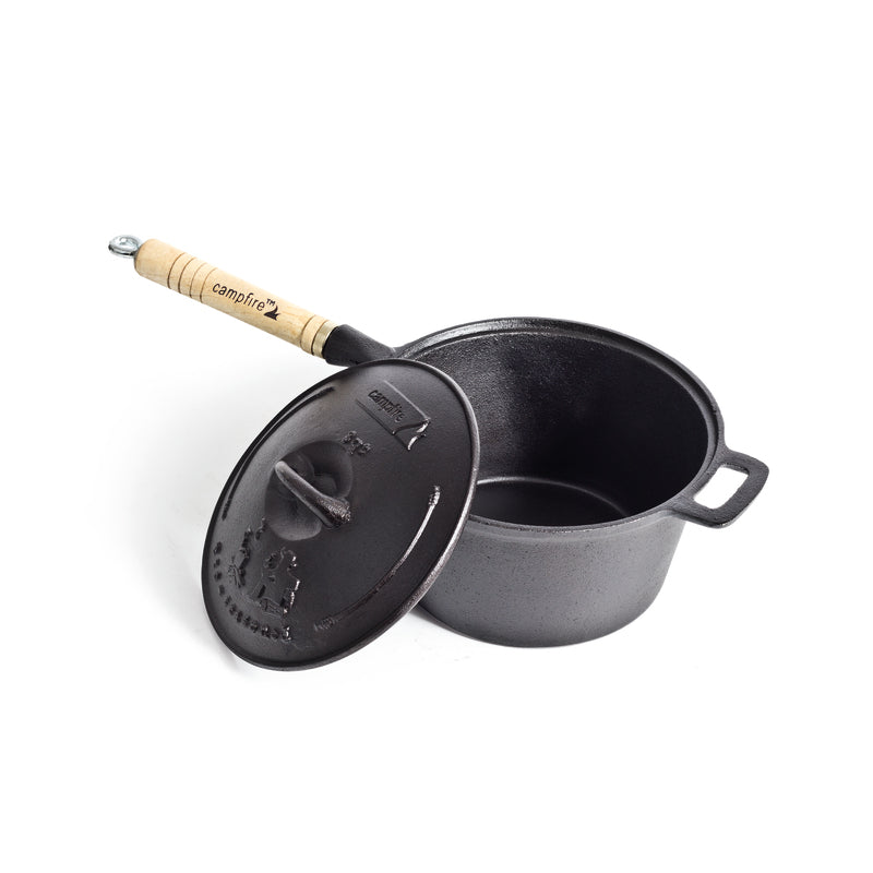 A 3 Quart Cast Iron Saucepan by Campfire, featuring a black finish, a lid, and a removable wooden handle, is displayed on a white background. The lid is partially tilted to reveal the interior of the pot and highlight its excellent heat retention.