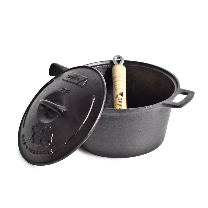 A Campfire 3 Quart Cast Iron Saucepan with exceptional heat retention is on display, its lid slightly ajar to reveal a removable wooden handle tool inside. The saucepan features two sturdy side handles, while the lid boasts a practical handle and embossed branding.