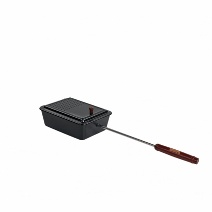 The Campfire Popcorn Pan, featuring a black metal design with a hinged lid, vent holes, and an extended metal handle with a wooden grip, is ideal for making fire-popped popcorn during campfire cooking—shown isolated on a white background.