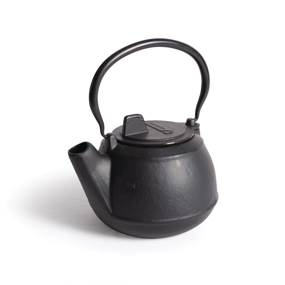 The Campfire 2 Quart Cast Iron Kettle features a rounded body, short spout, and sturdy arched handle—ideal for outdoor use or placing over a campfire. Photographed on a white background.