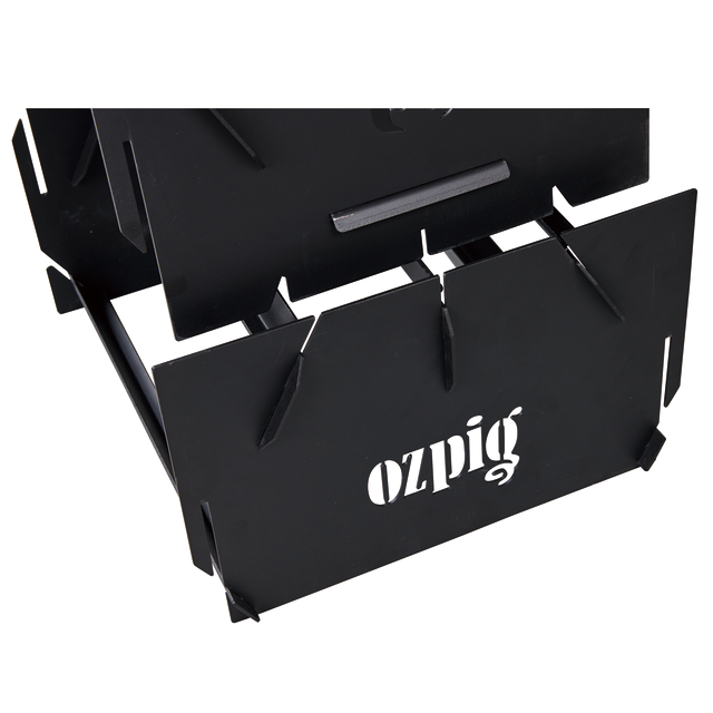 Close-up of the Ozpig 3-in-1 Flat Pack Fire Pit, a portable black metal fire pit with slotted edges, sturdy angular design, and the "Ozpig" logo cut out on its front panel.
