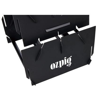 Close-up of the Ozpig 3-in-1 Flat Pack Fire Pit, a portable black metal fire pit with slotted edges, sturdy angular design, and the "Ozpig" logo cut out on its front panel.